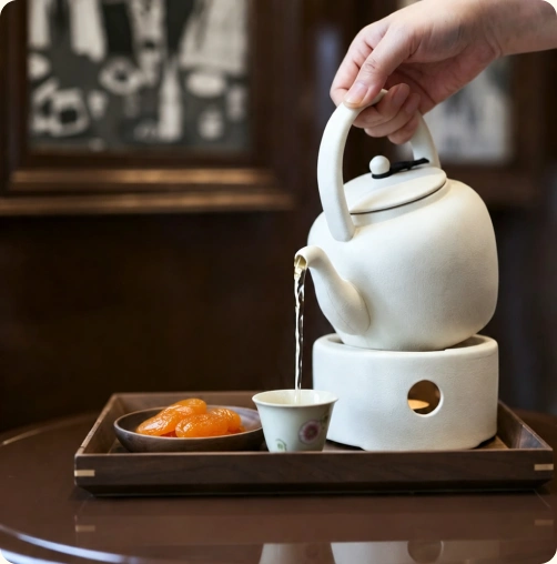 Tea being poured into a porcelain cup at YULIAN HOUSE